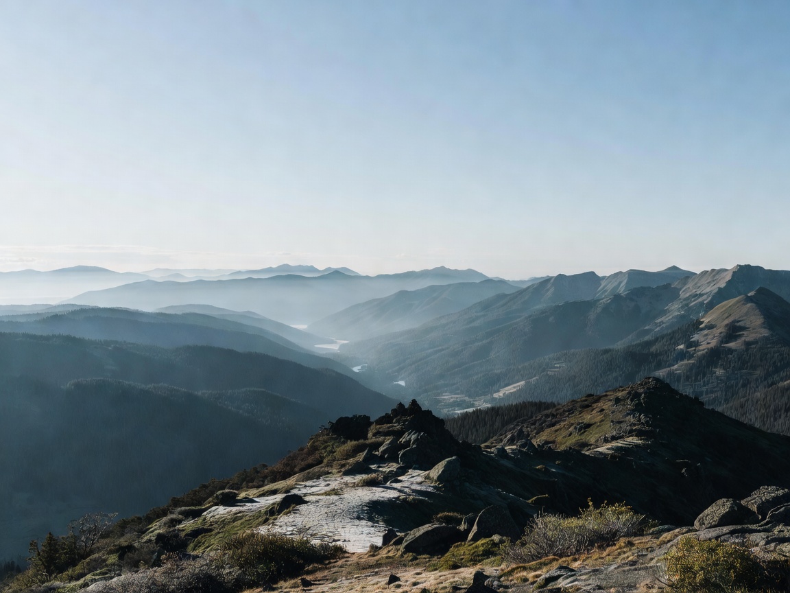 Ridgeline viewpoint with layered mountain valleys under cool morning sky